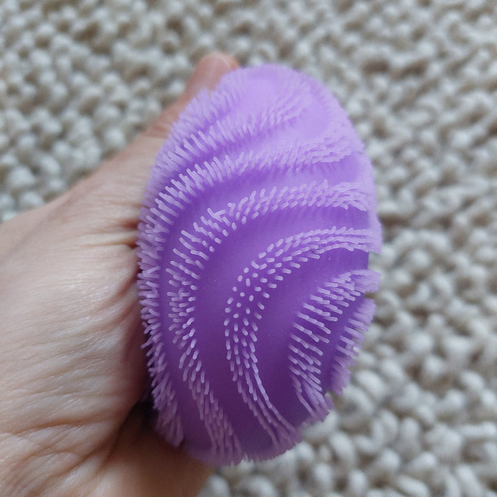 zachte harige fidget anti stressbal van needoh, fuzzy wave, sensoriek materiaal, paarse bal gedrukt in hand