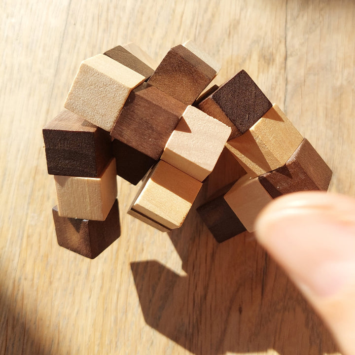 houten pocket puzzel, houten puzzelslang, tweekleurig op houten tafel