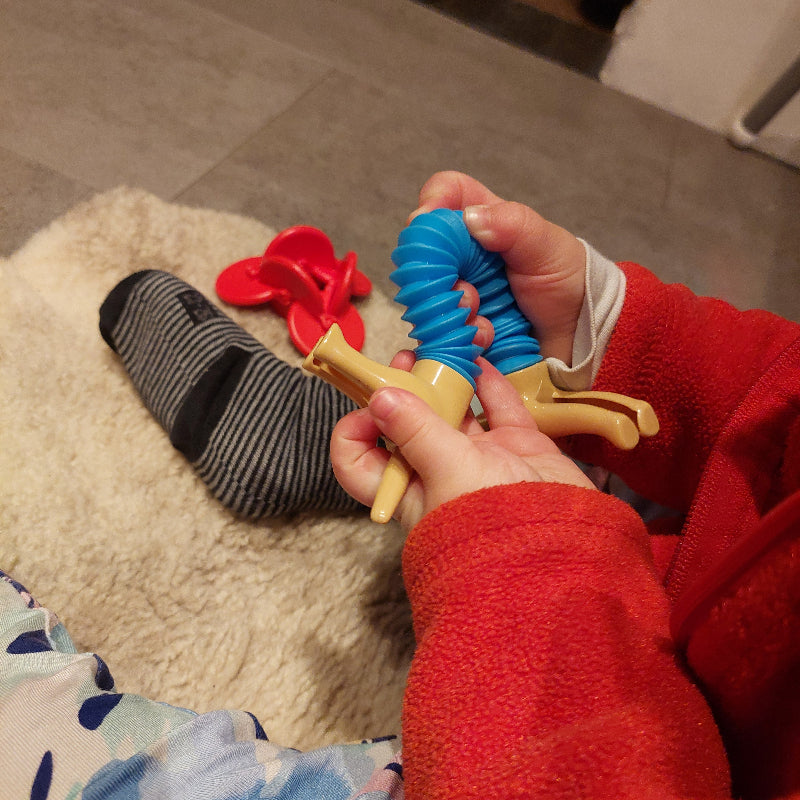 pop tube hond in babyhanden, kind aan het spelen, pop tube dog aan het buigen