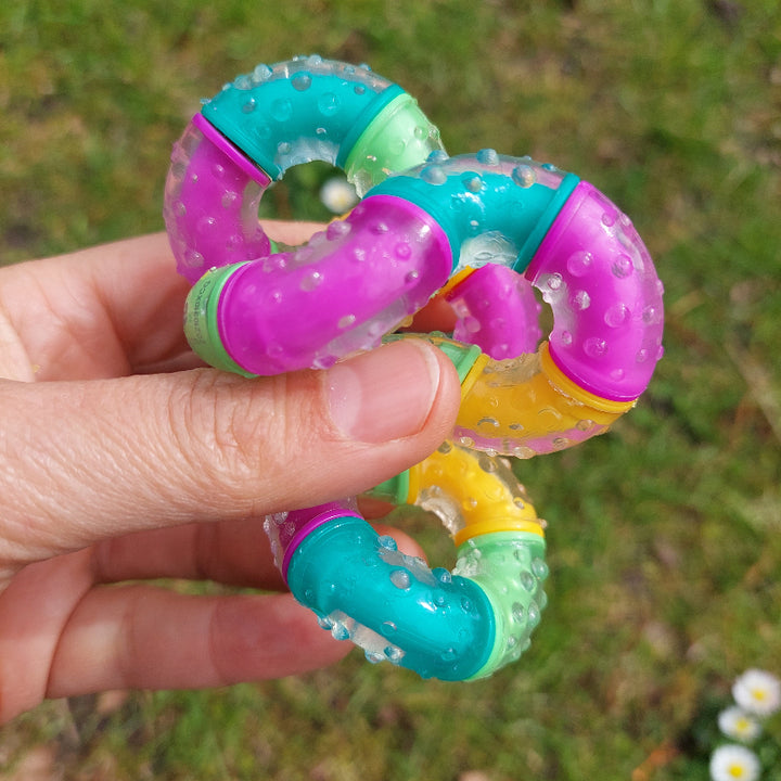 gedraaide therapy tangle think in velle kleuren, hand met achtergrond buiten