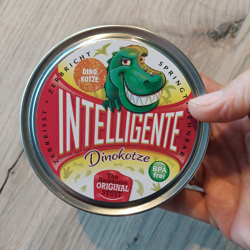 Intelligente knete, dino kotze, blik in hand, achtergrond houten tafel, si klei, sensoriek materiaal