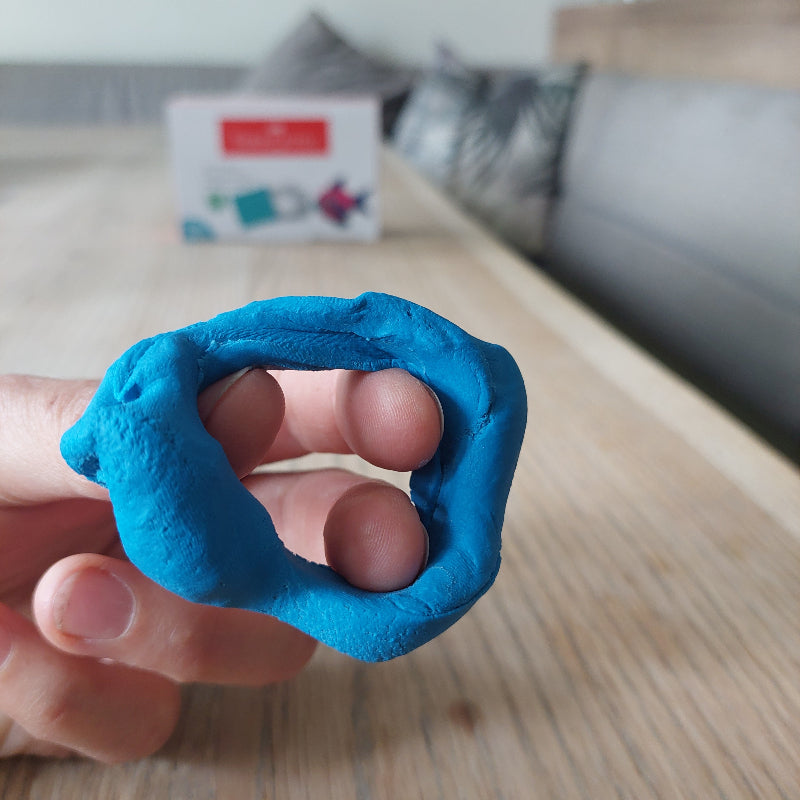 Kneedgum gebruikt als fingerkrachtoefening waarbij de vingers in een ring van klei stekken