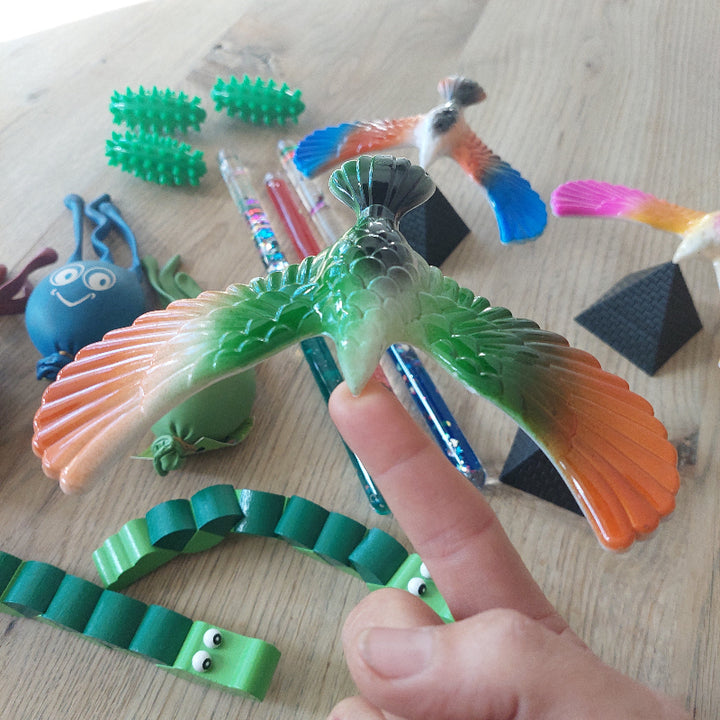 vingervogel op vinger als afleiding tijdens een prikmoment, met de overige materialen uit de afleidingsset op de achtergrond.