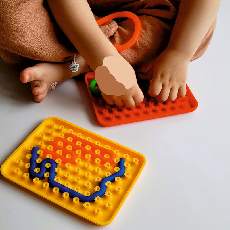 kind aan het spelen met silicone sensoriek speelgoed, plaat met wormpjes, stretch snoertjes