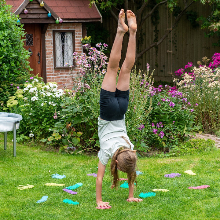 Kind maakt een handstand op kleurrijke sensorische hand- en voetvormen van siliconen