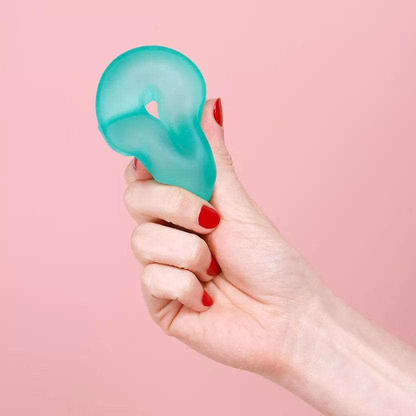 speks gump loop groen in hand met rode vingernagels en roze achtergrond, fidget van speks