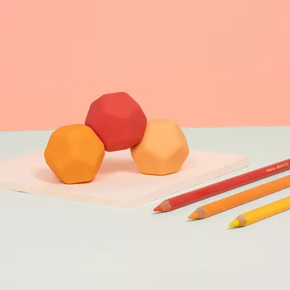 Drie SPEKS Odds oranje silicone fidget ballen met afgeronde rechte structuren op een bureau, los naast elkaar gepresenteerd
