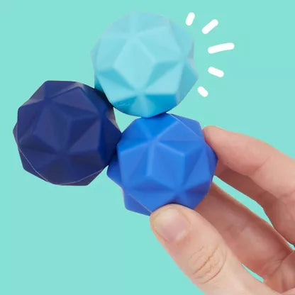 Drie blauwe SPEKS Odds silicone fidget ballen met driehoekige noppen in handen gehouden, tonen textuur en formaat