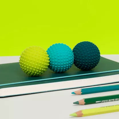 Drie groene SPEKS Odds fidget ballen met stekelige noppen op een rij op bureau, tonen formaat en structuur duidelijk