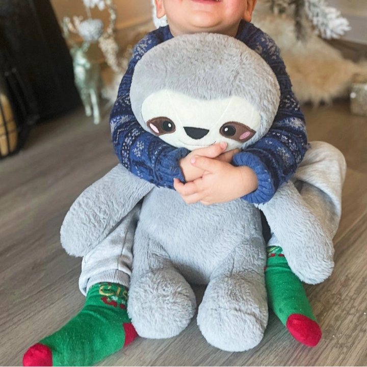 jong kind onder de kerstboom met verzwaarde knuffel op schoot, luiaard knuffel si materiaal, gewichtsknuffel