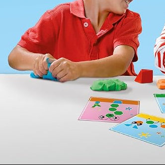 kind met blauw klei aan het kneden, opdrachtskaarten voor hem op tafel, motoriekspeelgoed