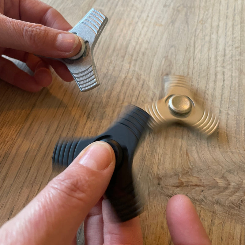 fidget spinner in handen, goud, zilver en zwart, zware aluminium spinner