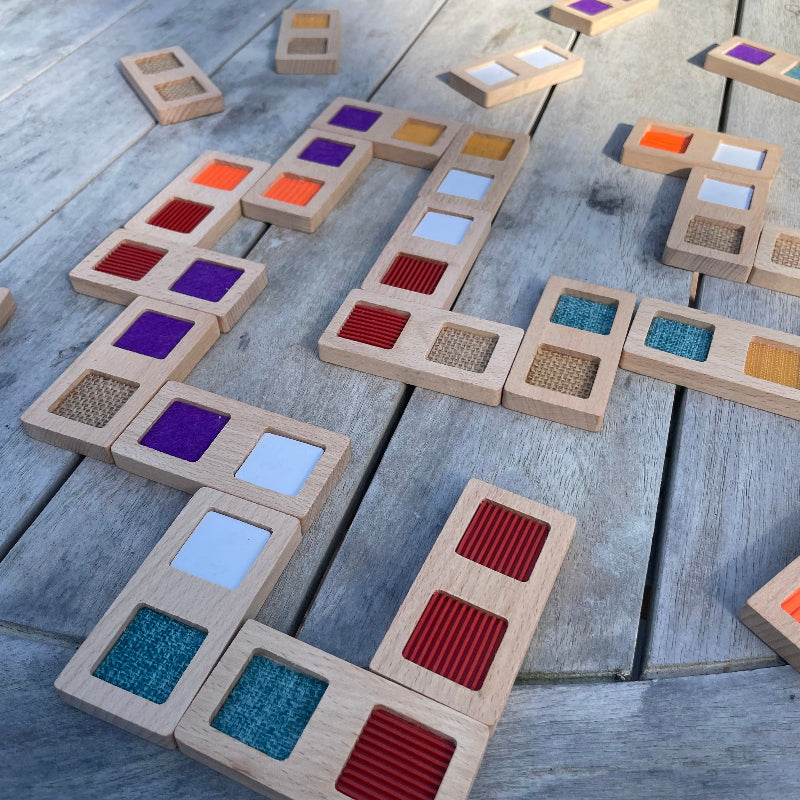 Structuur domino van andreu toys, made in eu, milieuvriendelijke sensoriek speelgoed, op houten tafel opgebouwd, kleuren, rood, turquiise, paars wit
