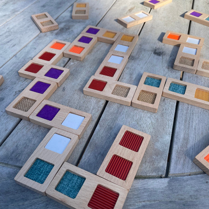 Structuur domino van andreu toys, made in eu, milieuvriendelijke sensoriek speelgoed, op houten tafel opgebouwd, kleuren, rood, turquiise, paars wit
