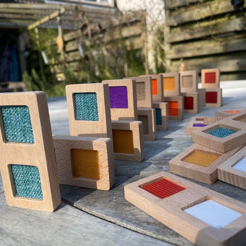 Structuur domino stenen buiten opgebouwd, verschillende stofjes als domino, prachtige kleuren, houten voelspeelgoed