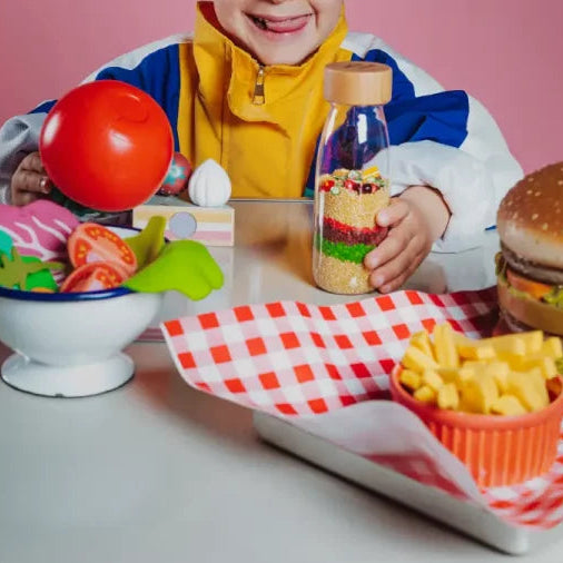 kind aan tafel met si fles van petit boum, Learn bottle macboum, si materiaal hamburger, patat