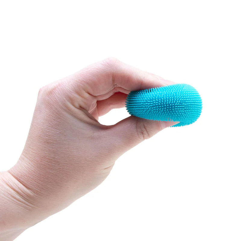 Hand die een blauwe NeeDoh Teenie Fuzz Ball vasthoudt en indrukt