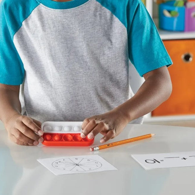kind rekend met de ten frame pop it rekenrekjes van learning resources, rekenmateriaal