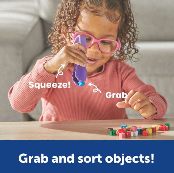 Kind grijpt kleinen blokjes met kindertang. Learning resources motoriekmateriaal