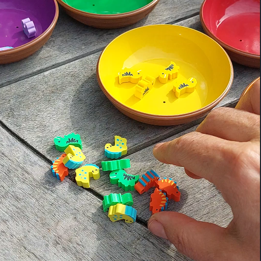 hand grijpt naar mini gum dino, fijne motoriek materiaal