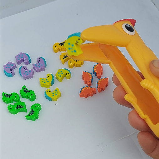specht pincet grijpt gele mini gum, mini gum dino's in verschillende kleuren op de achtergrond