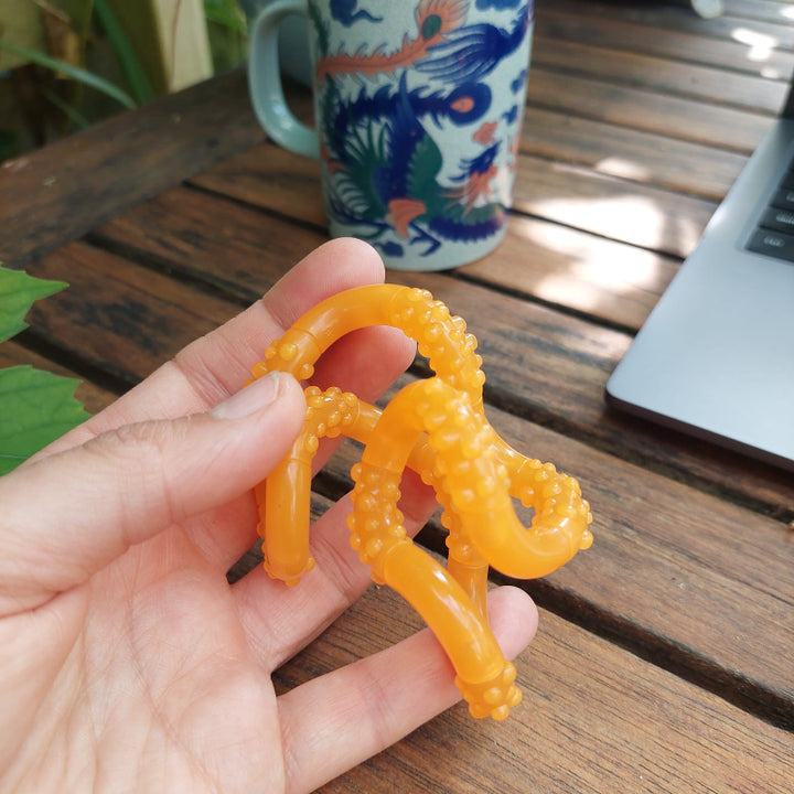glow in the dark tangle, tangle tangerin, tangle structuur oranje, fidget, friemelspeelgoed, tangle in hand bij laptop met kopje thee