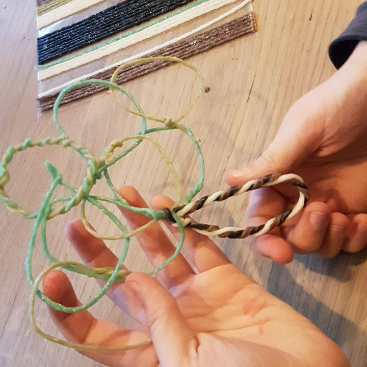 handen die Wikki Stix in natuurlijke kleuren buigen en vormen tot figuren