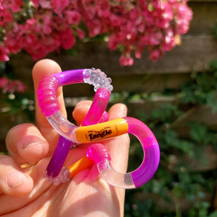 Tangle Tangle structuur oranje-roze-paars in hand voor roze bloemen in de zon
