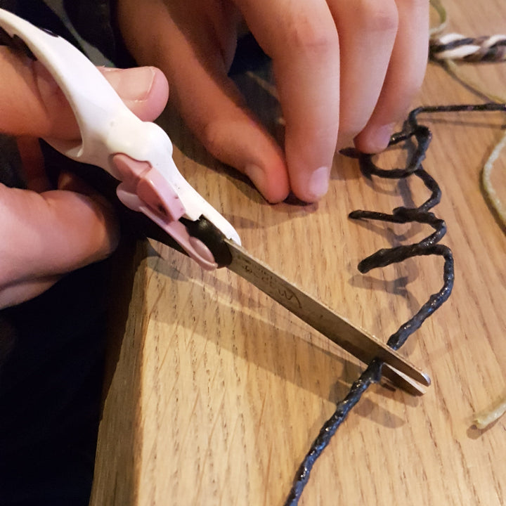 handen die Wikki Stix in natuurlijke kleuren met een schaar knippen