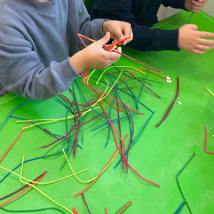 Wikki Stix Basiskleuren 48 stuks, handen die Wikki Stix in neon kleuren buigen en vormen
