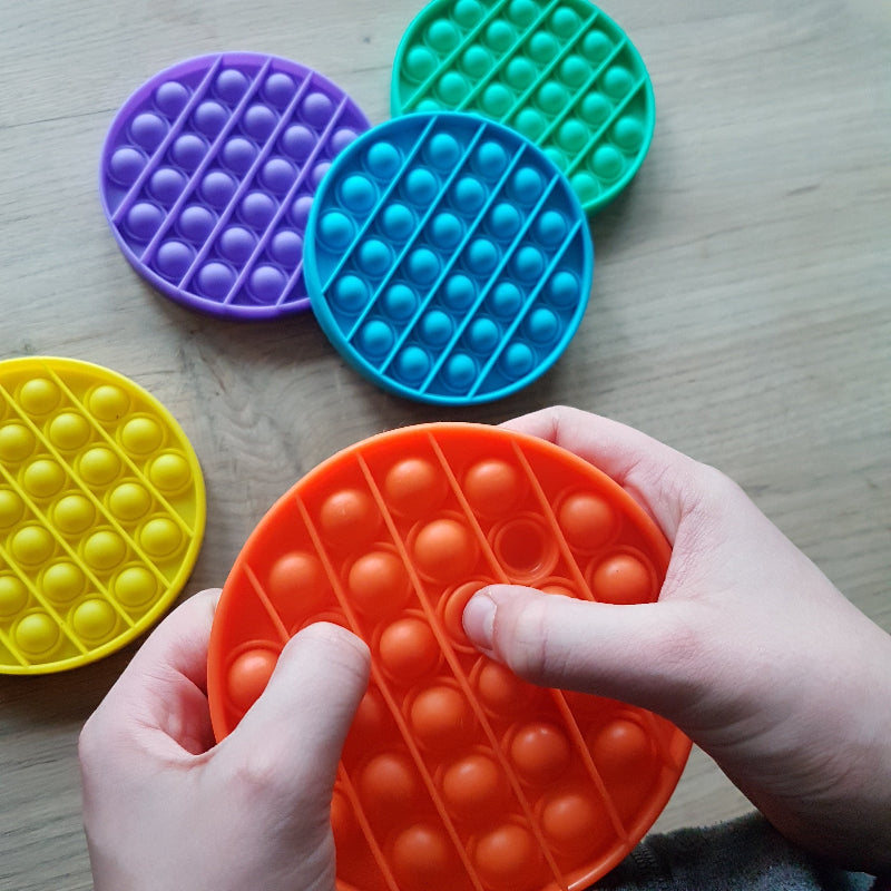Toys42Hands Pop it rond, rage, fidget speelgoed in verschillende kleuren met twee handen op de foto
