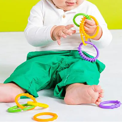 Kind ontdekt sensorische speelringen Lots of Links met verschillende structuren, links tot ketting aan elkaar gemaakt, motoriekspeelgoed, babyspeelgoed