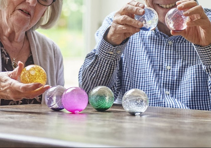 senioren spelen met de glitterballen van tickit, motoriekspeelmateriaal