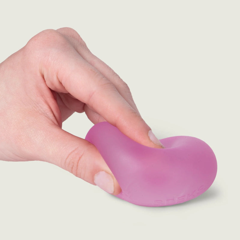 SPEKS Gump Original stressbal in kleur Moon Jelly roze, hand drukt de bal op tafel, toont soepele en kneedbare structuur, fidget