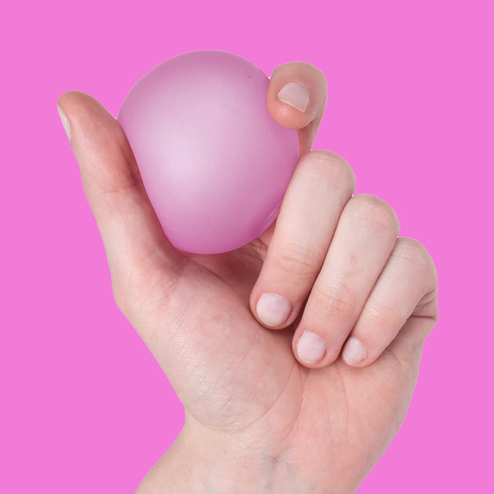 SPEKS Gump Original stressbal in kleur Moon Jelly roze in hand geknepen, toont soepele en kneedbare structuur